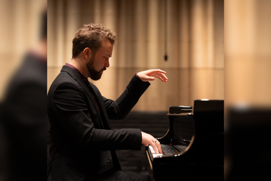 Pianist Sander C. Lekkerkerk vanaf de zijkant aan een piano
