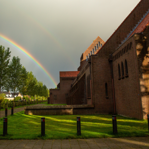 Bedevaartkerk Brielle vanaf buiten. Er is links een regenboog te zien